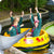 Children in a yellow boat with animal illustrations, surrounded by water and greenery.