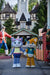 Two cartoonish cat mascots holding hands in front of a themed building.