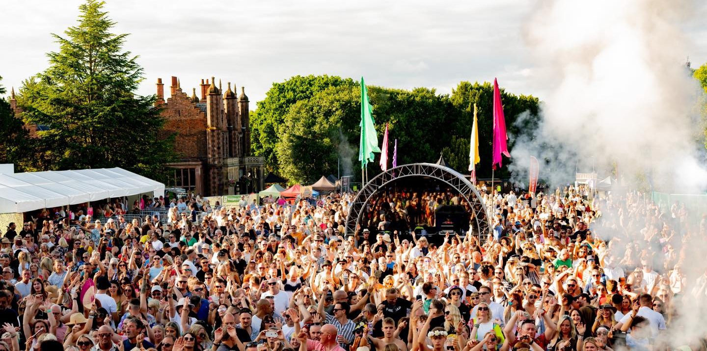 Large outdoor concert with a crowd and stage in front of a historic building.