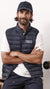 A man wearing a navy blue Stanley/Stella puffer vest over a white t-shirt and dark pants, posing with his arms crossed against a light background.