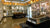 Museum exhibit with glass cases displaying artifacts, including a mummy, in a large room.