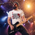 A bearded man wearing a custom-printed band merchandise T-shirt playing guitar on stage