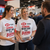 Two women at a trade conference wearing matching white company-branded T-shirts.