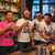 Four men laughing and celebrating in a bar setting, wearing matching graphic T-shirts. Three shirts are white with black 'STAG CREW' text and antler graphics, while one shirt is bright pink with 'GROOM GAME OVER' text.